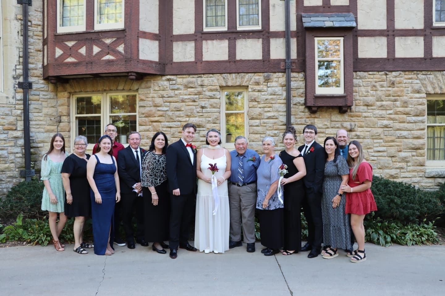 A large family group photo in front of the Tudor facade of the Plummer House