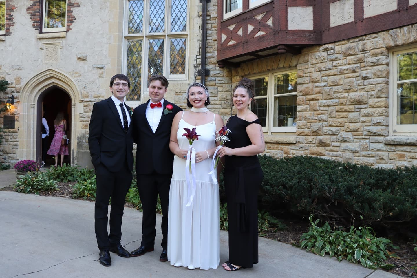 Abbi and Fred with members of the wedding party by the house's arched doorway
