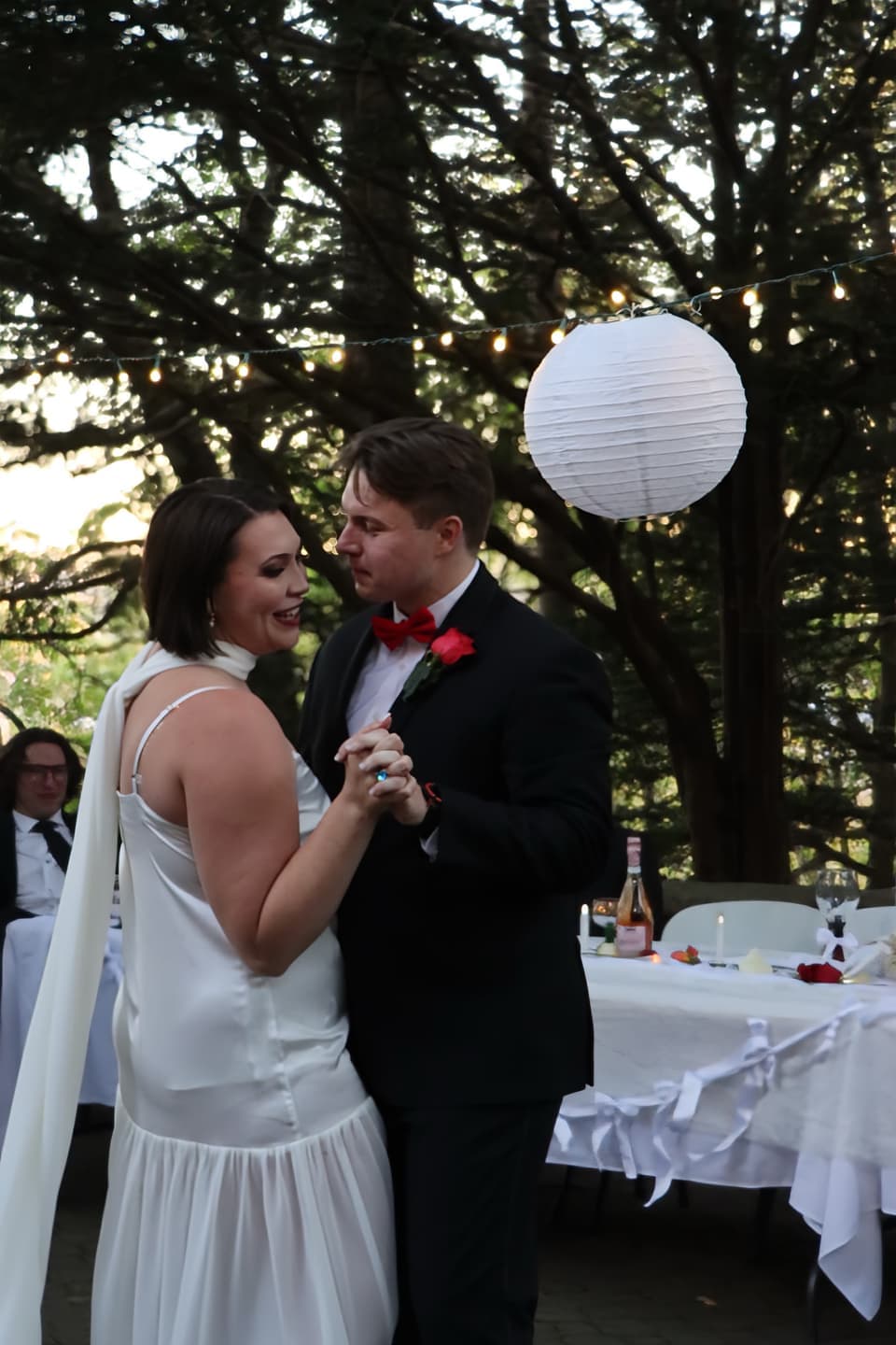 Abbi and Fred's first dance under white paper lanterns at dusk