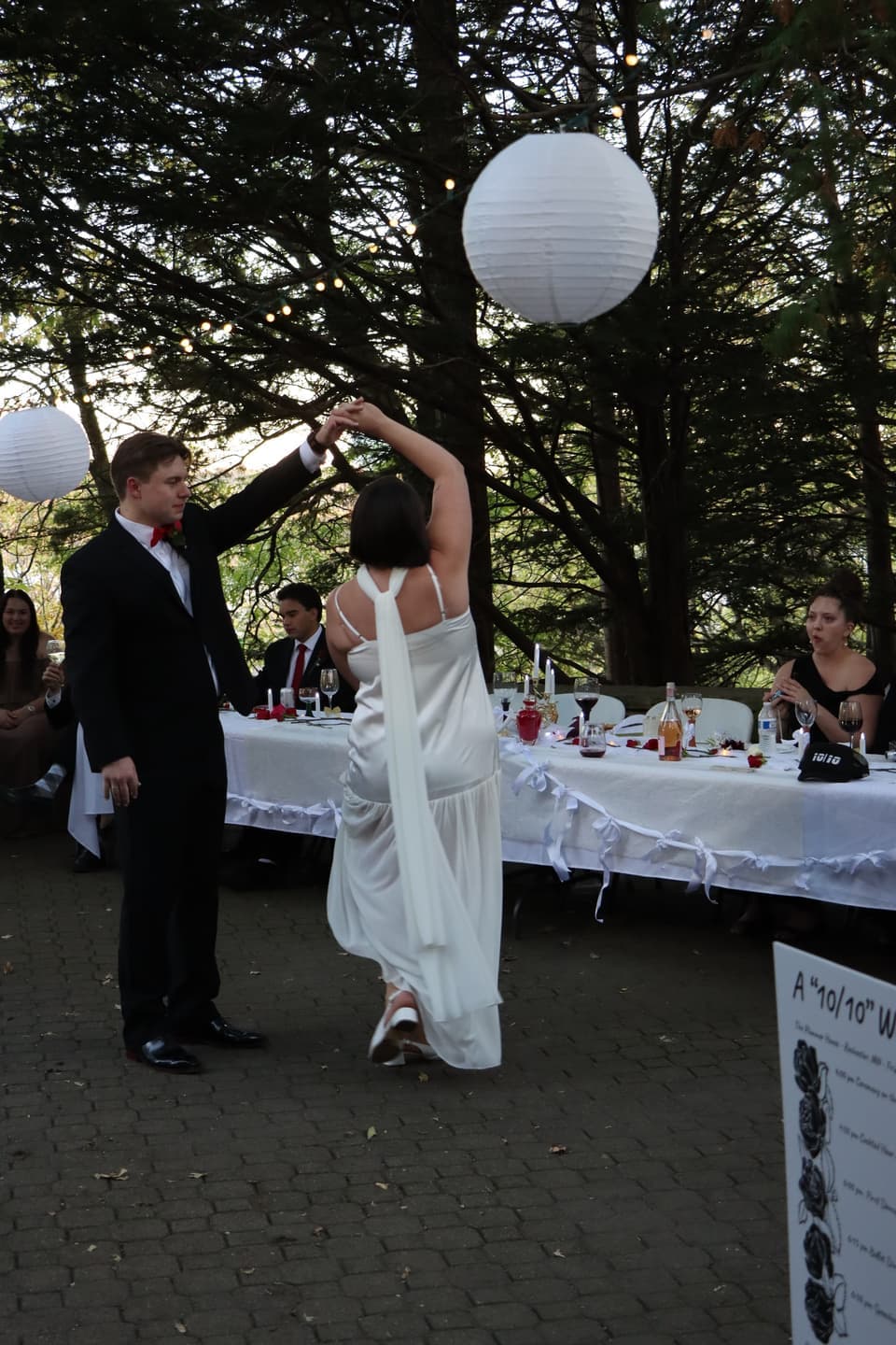 Fred twirls Abbi on the patio beside the reception tables